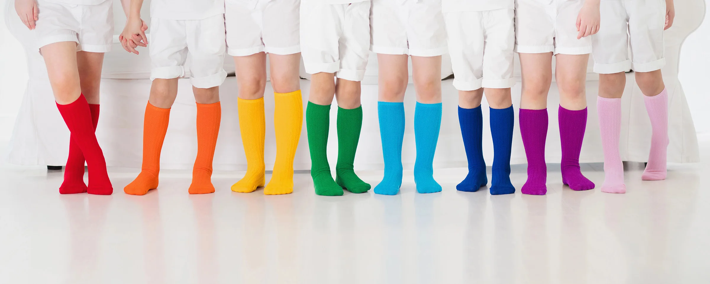 Several kids wearing multi-colored socks.