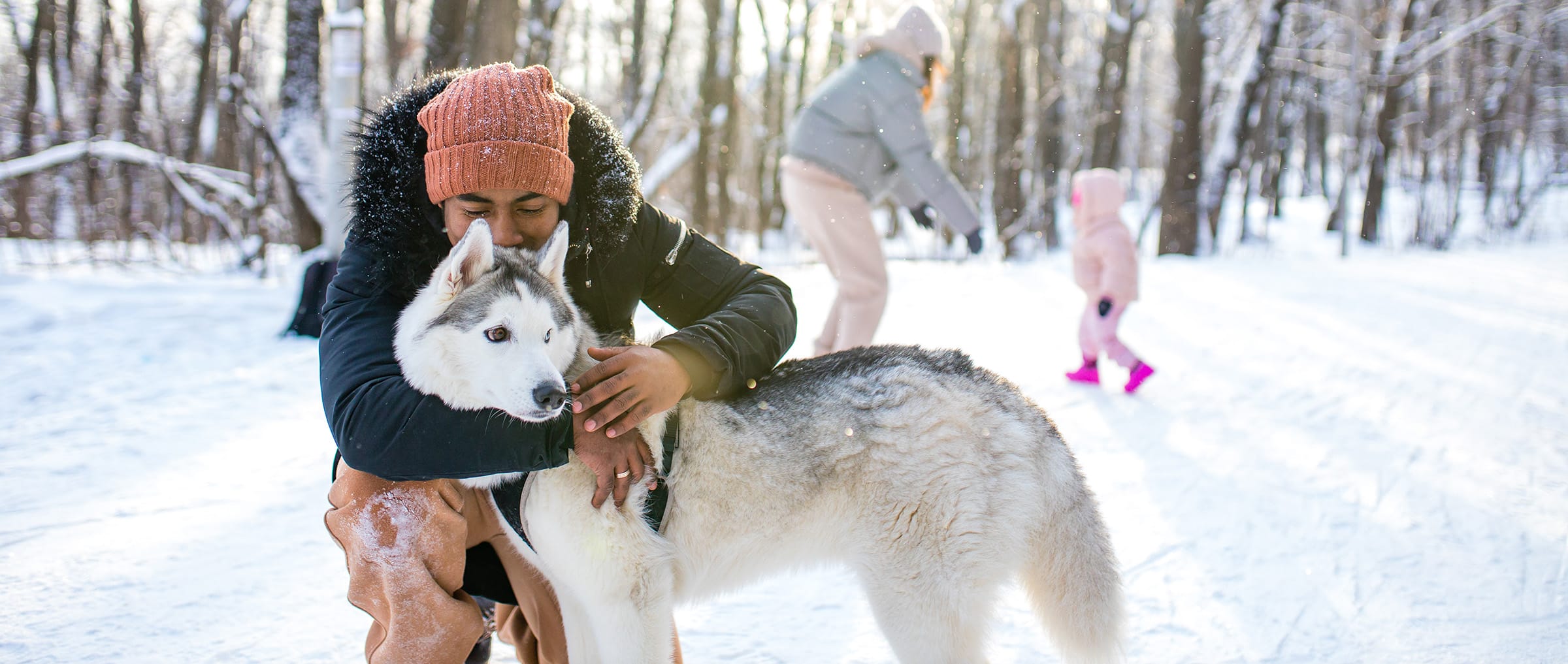Man with husky outside in the snow dressed for winter.