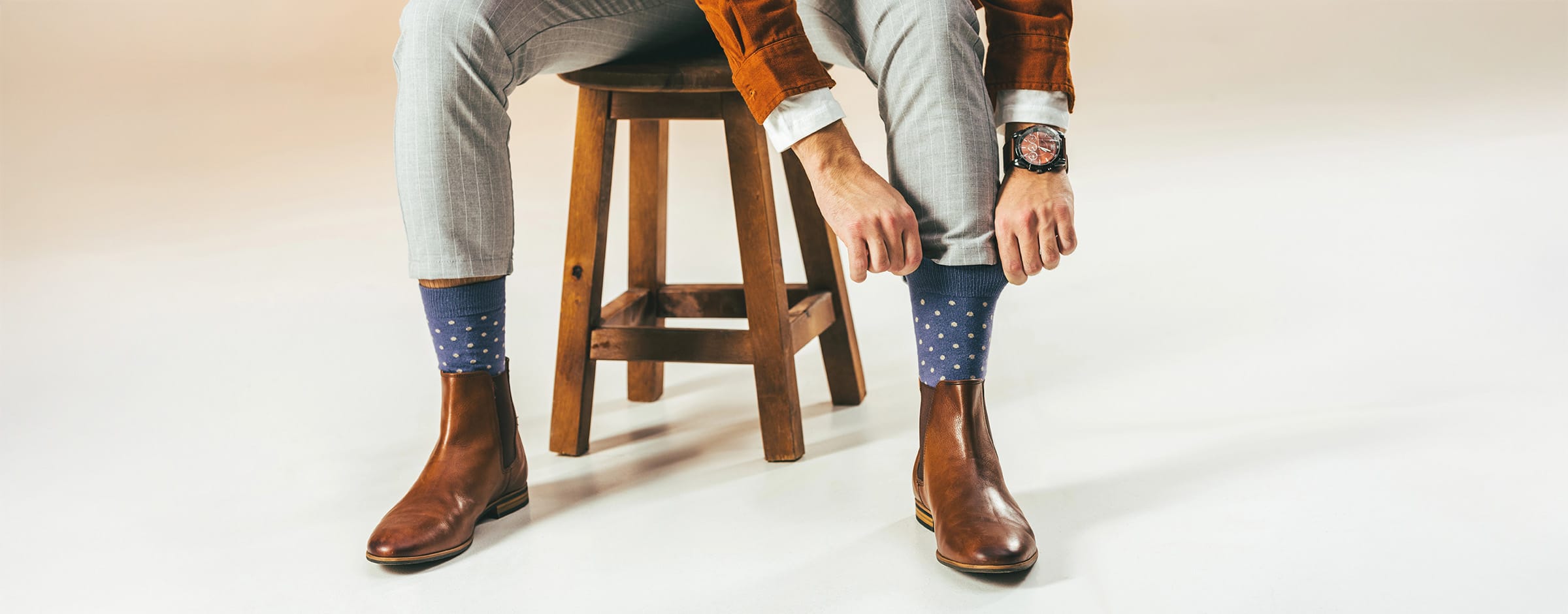 Man adjusting blue socks with white dots.