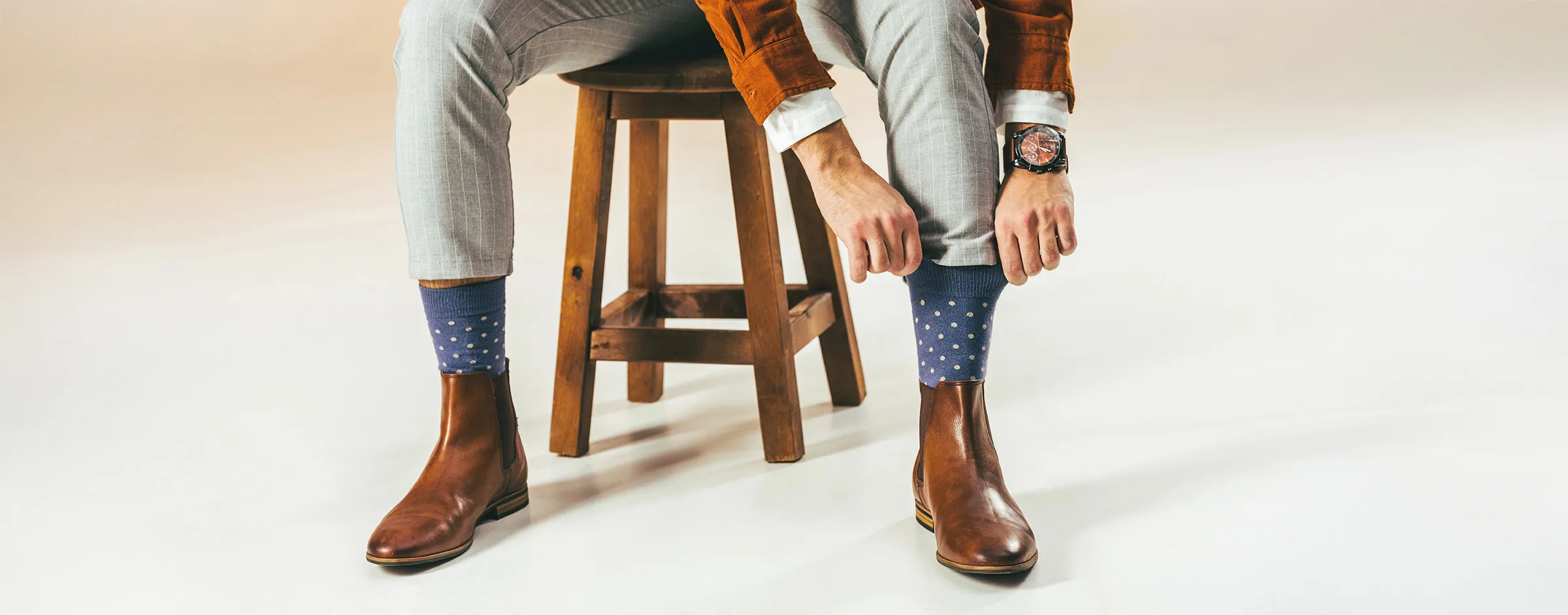 Man adjusting blue socks with white dots.