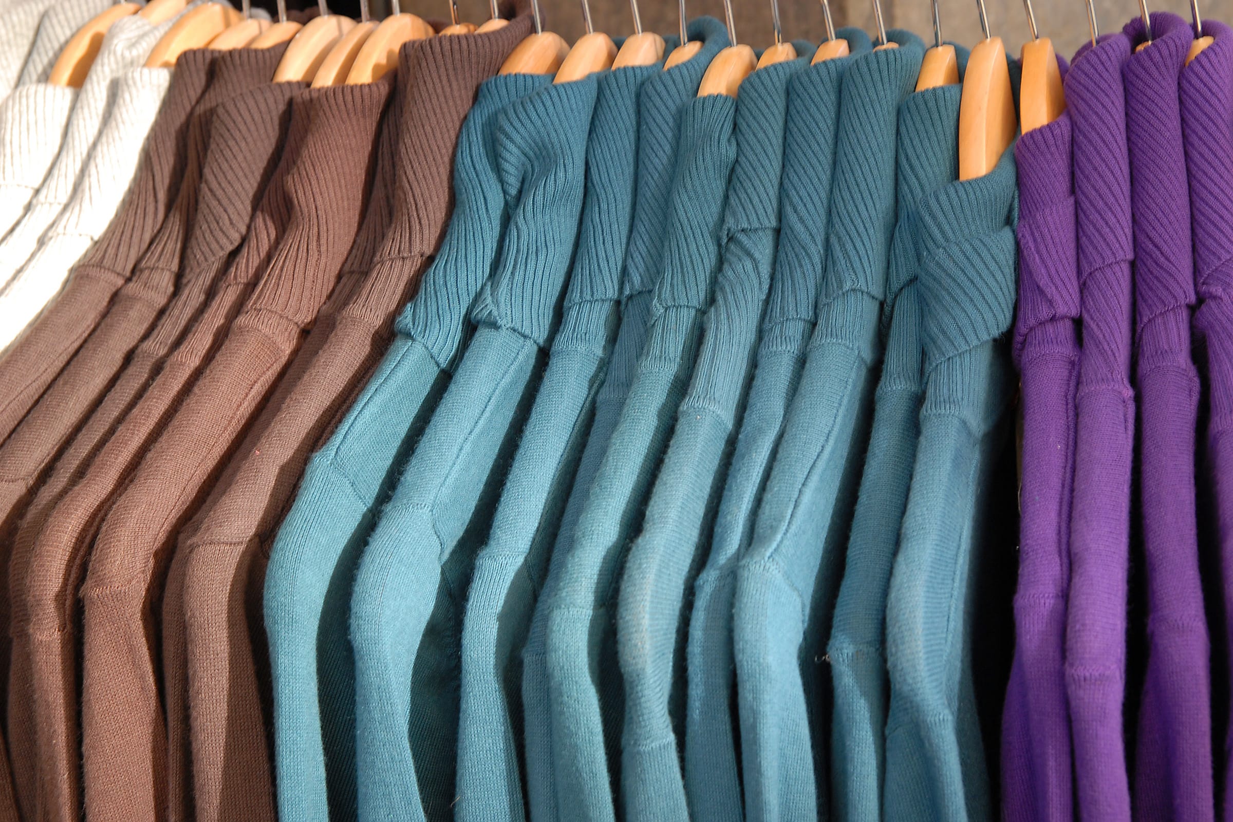 Row of sweaters on a clothes rack.