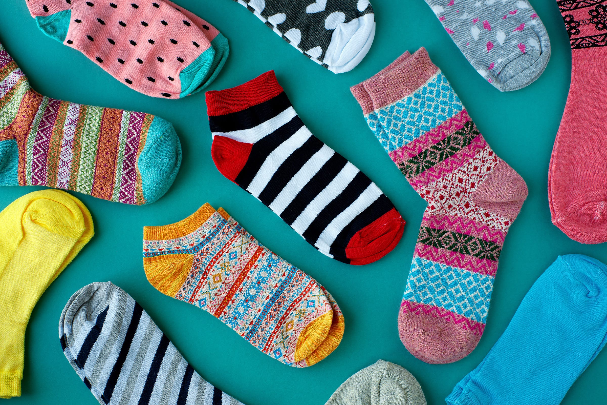 Multiple pairs of different colored socks on a blue background.