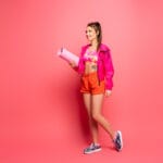Woman in athletic wear carrying a yoga mat.