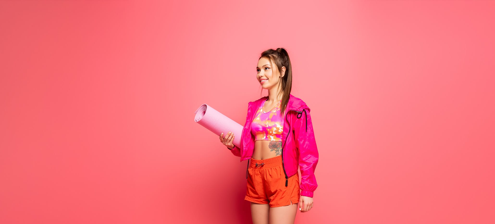 Woman in athletic wear carrying a yoga mat.