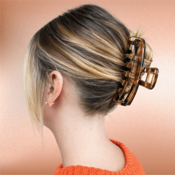 Blonde hair styled in a low twist secured with a tortoise shell rectangular claw clip against a soft peach background.