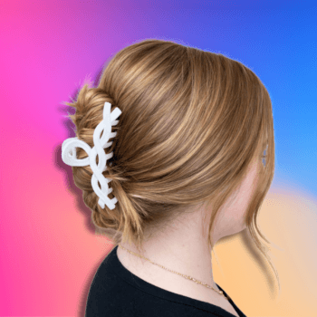 Light brown hair styled in a messy bun secured with a matte white twisted claw clip against a vibrant gradient background.
